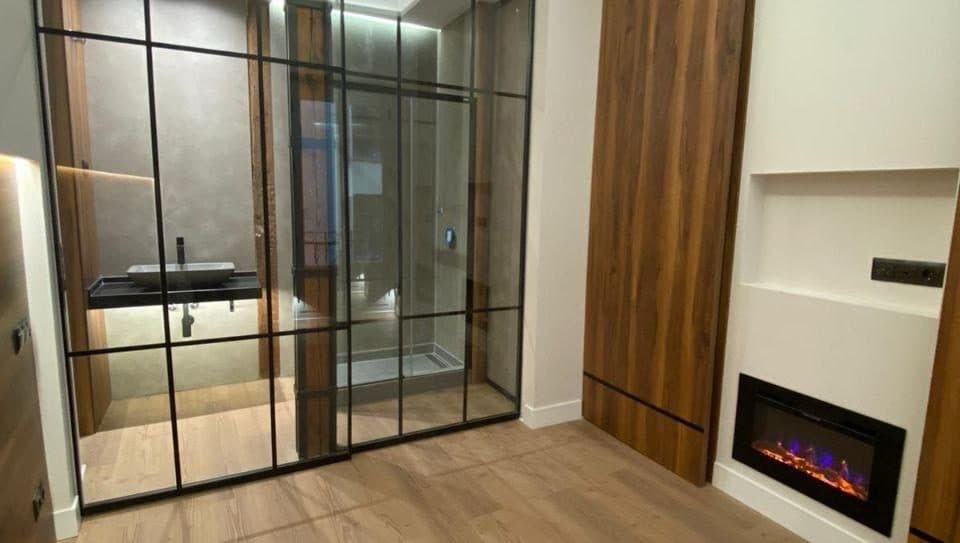 Dormitorio reformado con baño en suite tras tabique de cristal, madera y chimenea, Madrid